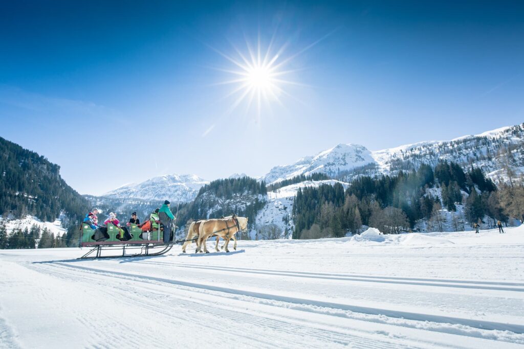 Familie bei einer Pferdeschlittenfahrt während ihres Winterurlaubs in Obertauern